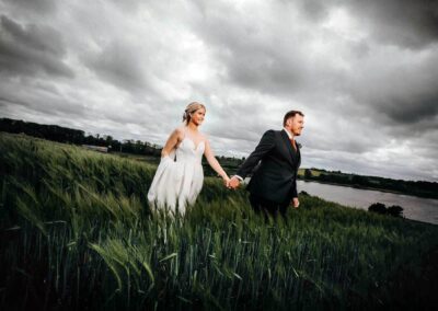 bruden og gommen fotograferet sammen på en mark med en tung himmel bagved